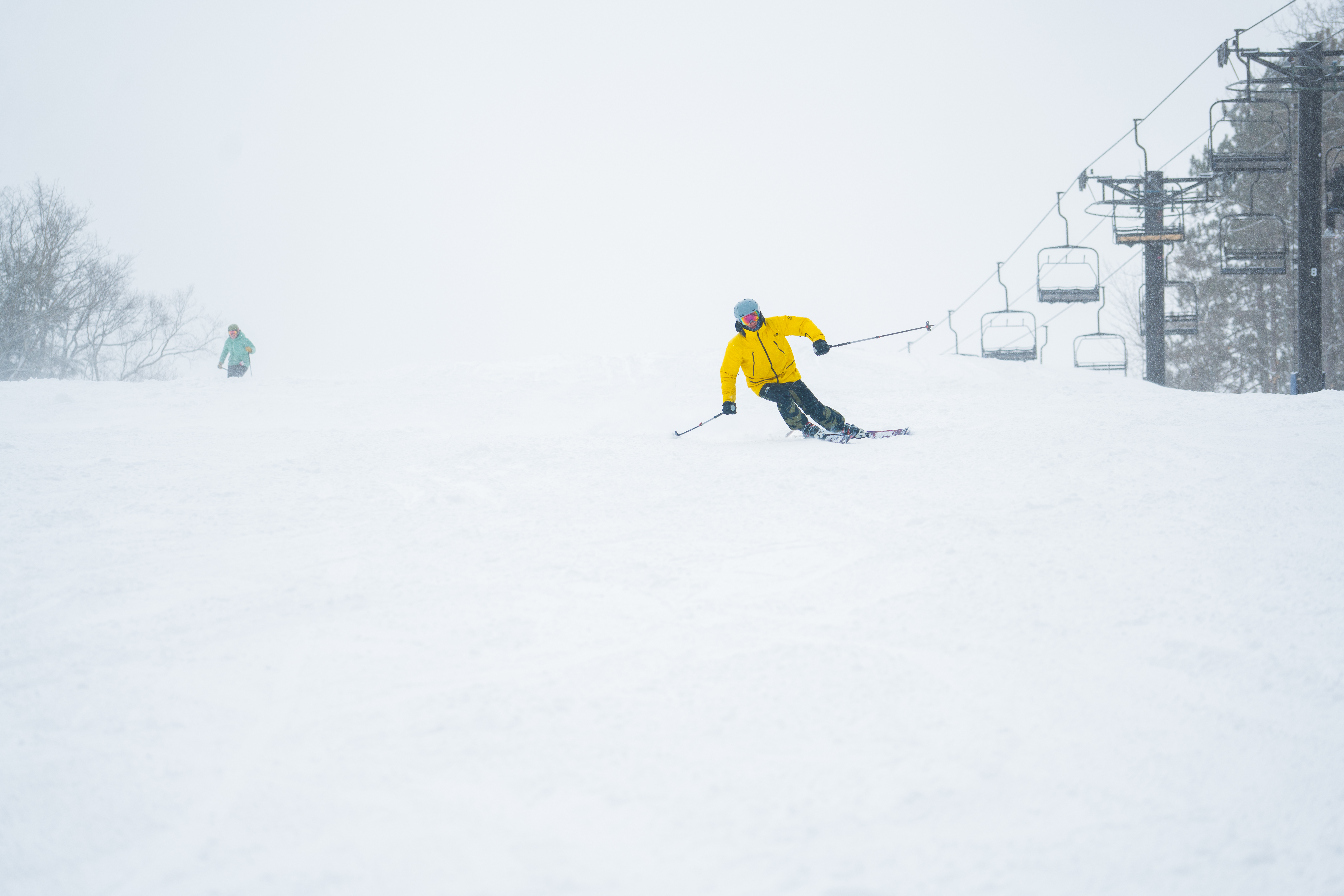 Skier going down mountain with lifts in the background.